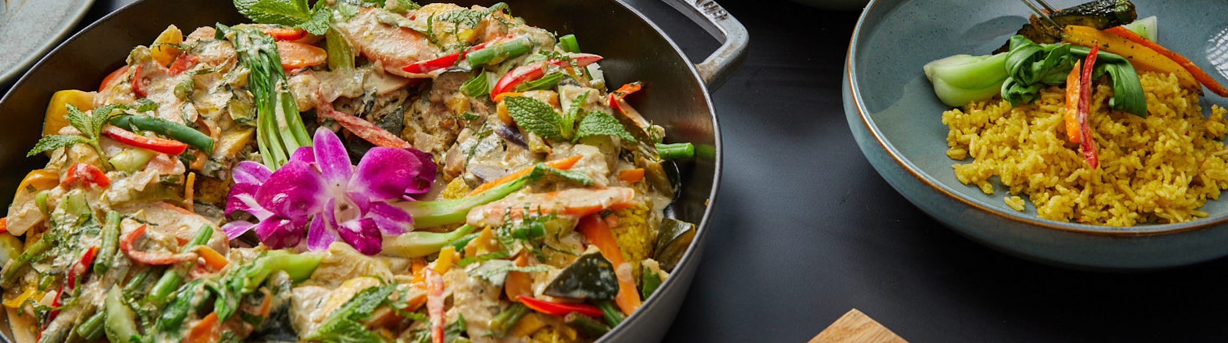 Thai green vegetable curry is on display in a large bowl with a serving to the right of it.