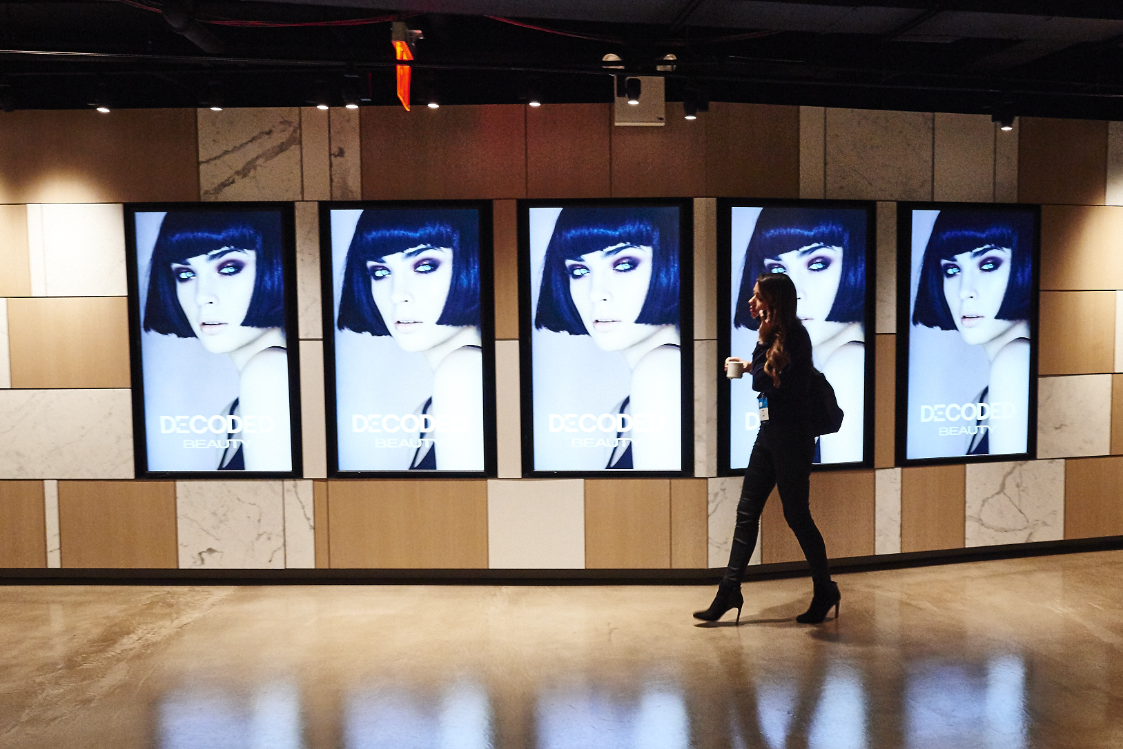 Woman walking in front of display screens